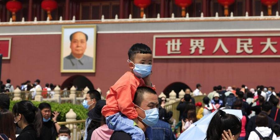 A man and child wearing masks visit Tiananmen Gate near the portrait of Mao Zedong in Beijing.