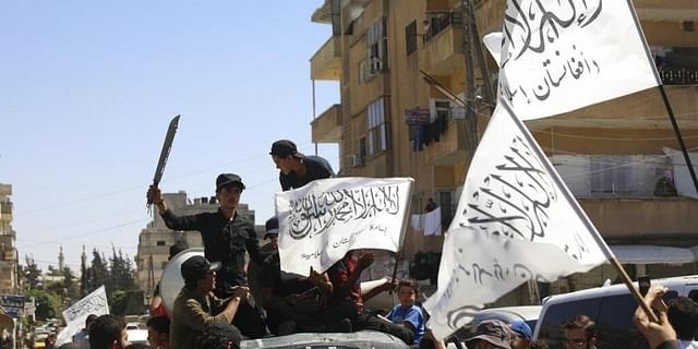 Members of the Hay'at Tahrir al-Sham, a Sunni Islamist militant group, wave the Taliban flags as they celebrate the Taliban takeover of Afghanistan, in the city of Idlib. 