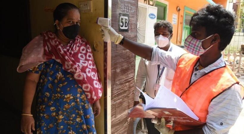 A healthcare worker conducts thermal screening on a woman in Chennai as coronavirus cases surge.
